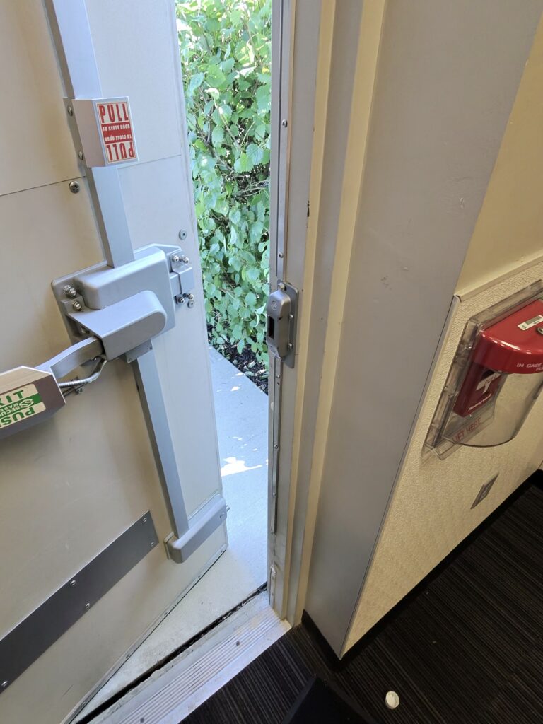 Commercial exit door with push bar and vertical rod locking hardware